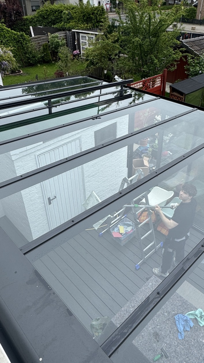 Mitarbeiter von Schütt Hand in Hand reinigt eine große Glasfläche schonend mit dem Reinwassersystem
